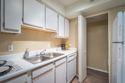 A kitchen with white cabinets and a white fridge.