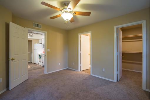 A room with a ceiling fan and carpeted floor.