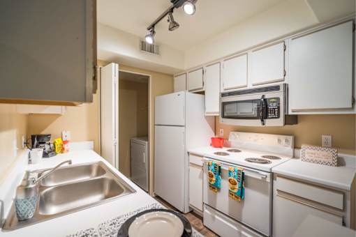 A small kitchen with white appliances and a white sink.