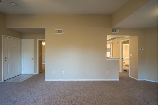 A large empty room with carpeted floor and white walls.