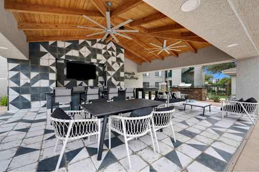 A patio with a table and chairs under a wooden ceiling.
