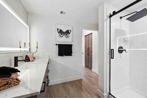 a bathroom with white walls and a black and white painting on the wall