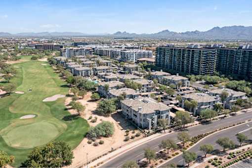 an aerial view of apartments and a golf course with mountains in the background