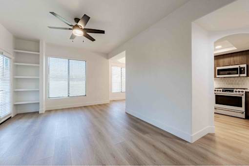 an empty living room with a ceiling fan