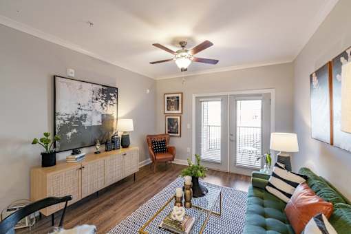 A living room with a green couch and a ceiling fan.