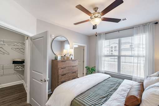 A bedroom with a large bed, a dresser, a mirror, and a ceiling fan.