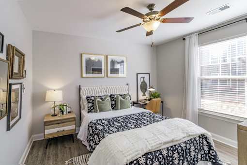 A bedroom with a bed, nightstand, and a ceiling fan.