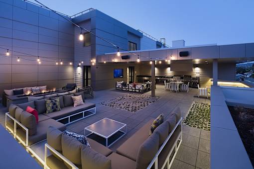 A modern outdoor seating area with a glass table and comfortable couches.