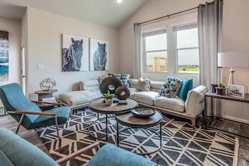 A living room with a white couch, blue chairs, and a rug.