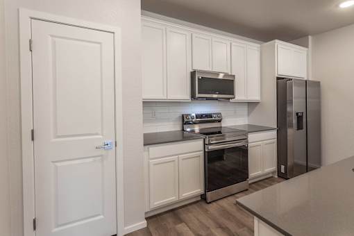 A kitchen with white cabinets and a stainless steel refrigerator.