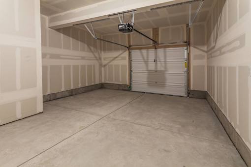 A spacious garage with a closed white door and a ceiling light.