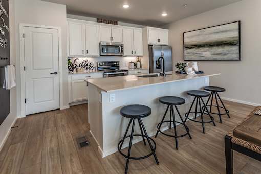 A kitchen with white cabinets and a black fridge.