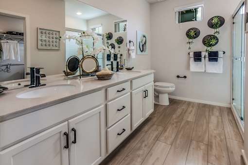 A bathroom with a white counter top and wooden floors.