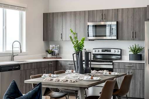 A modern kitchen with a dining table set for two.