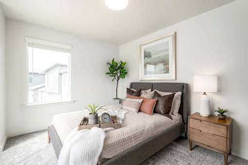 A bedroom with a bed, nightstand, and a window.