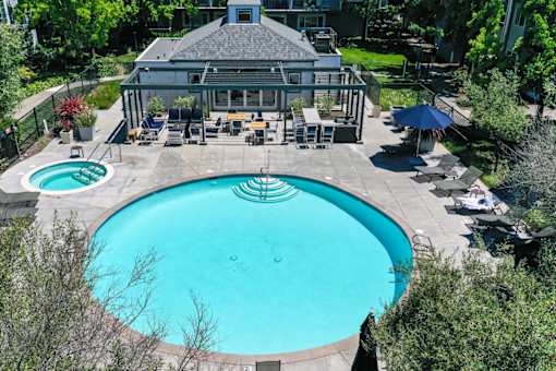 A large swimming pool surrounded by a patio with chairs and a gazebo.