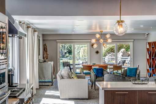 A modern living room with a large window and a dining area.