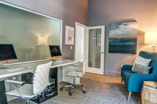 A modern home office with a desk, chair, and a painting on the wall.