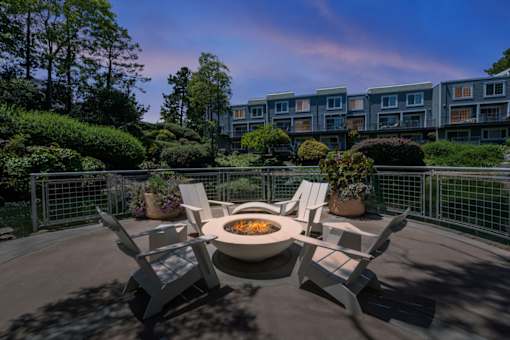 A fire pit sits in the middle of a patio surrounded by four chairs.