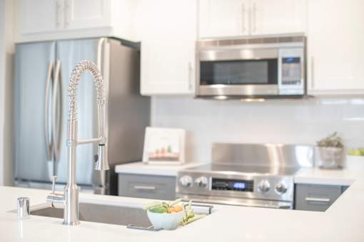A modern kitchen with a stainless steel refrigerator and microwave above a stove.