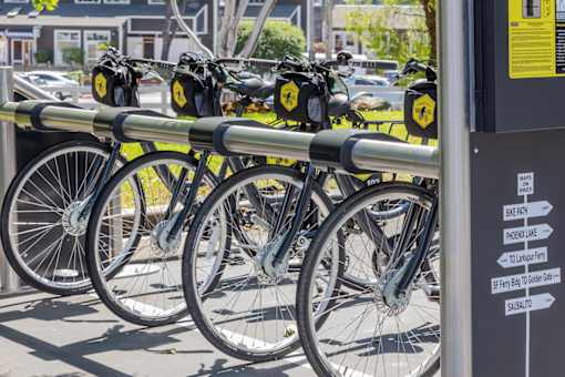 A row of bicycles are parked at a bike rack.