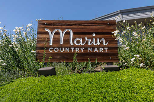 A wooden sign that says "Marin Country Mart" in front of a building.