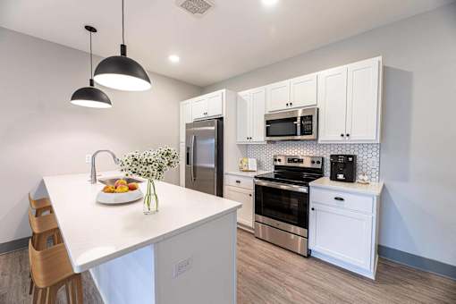 A kitchen with white cabinets and a white island with a sink.