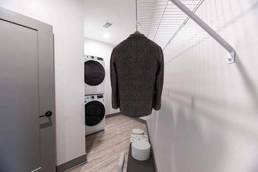 A brown sweater hanging on a rail in a laundry room.