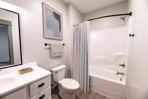 A white bathroom with a toilet, sink, and shower.