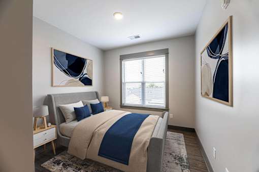 A bedroom with a bed, a nightstand, and two paintings on the wall.