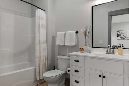 A white bathroom with a toilet, sink, and shower.