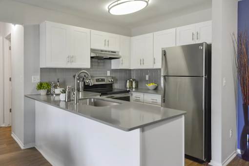 Bright kitchen with white cabinets and stainless steel refrigerator at The Villas at Northstar apartments for rent in Ann Arbor, MI