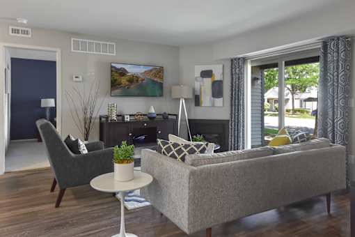 Living room with couch, chair, table and curtains at The Villas at Northstar apartments in Ann Arbor, MI