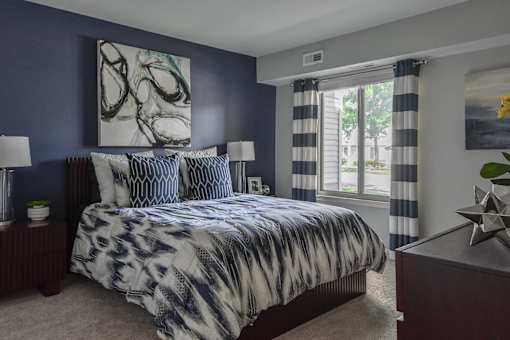 A bedroom with a large bed and a painting on the wall.