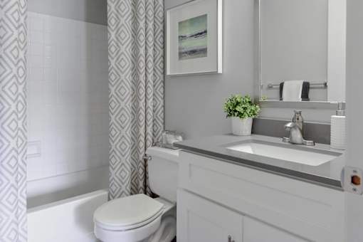 A white bathroom with a toilet, sink, and a framed picture on the wall.