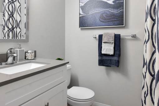 A bathroom with a toilet, sink, and a picture on the wall.