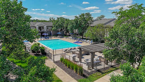 A pool surrounded by trees and a fence.