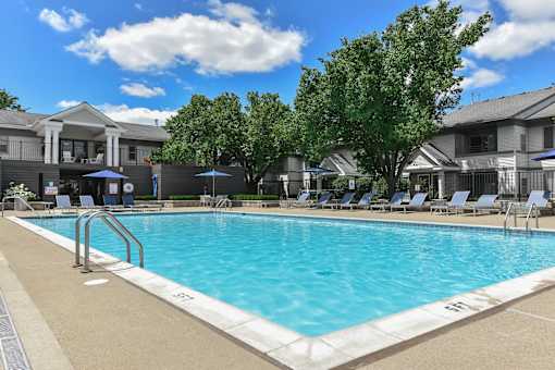 A swimming pool surrounded by lounge chairs and umbrellas.