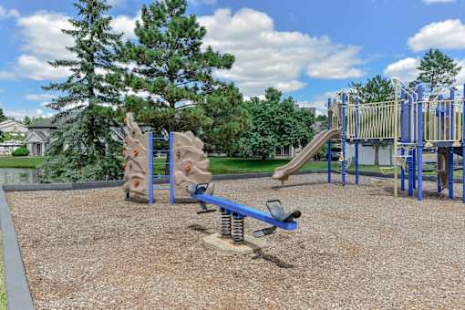 A playground with a slide, swings, and a seesaw.