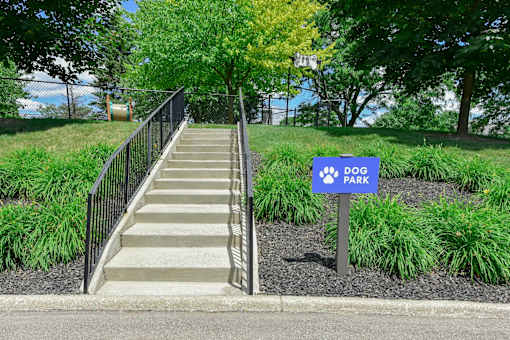 A set of stairs leads to a park with a sign on the right.