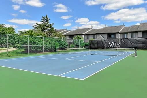 A tennis court with a net and a sign that says "VILLAS".