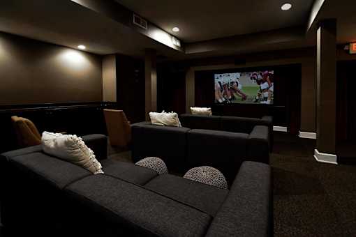 A dark room with a large screen and comfortable seating.