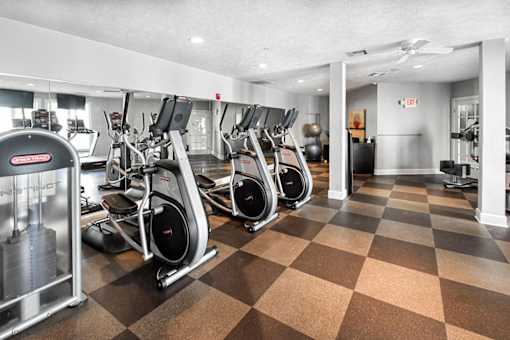A gym with a variety of exercise equipment including treadmills, stationary bikes, and elliptical machines.