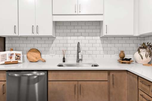 A kitchen with a stainless steel dishwasher and wooden cabinets.