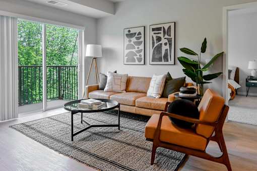 A living room with a sofa, a chair, a coffee table, and a potted plant.
