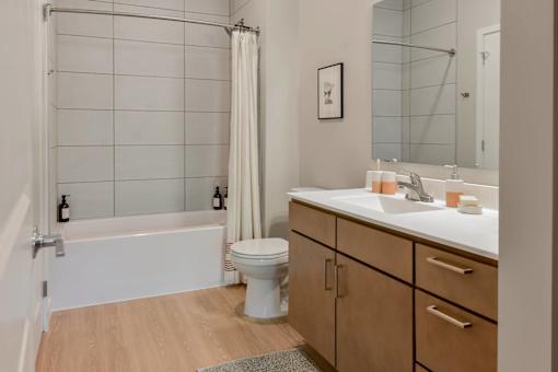 A white toilet sits in a bathroom with a white tub and a sink.