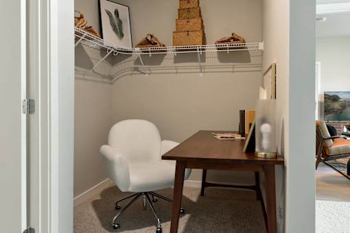 A white chair is in front of a desk with a white shelf above it.