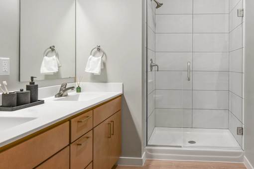 A bathroom with a white sink and a glass shower stall.