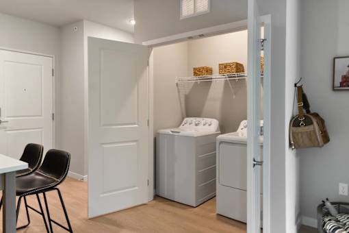A laundry room with a washer and dryer and a chair.