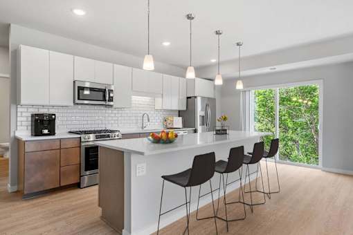 A modern kitchen with a white island and black barstools.